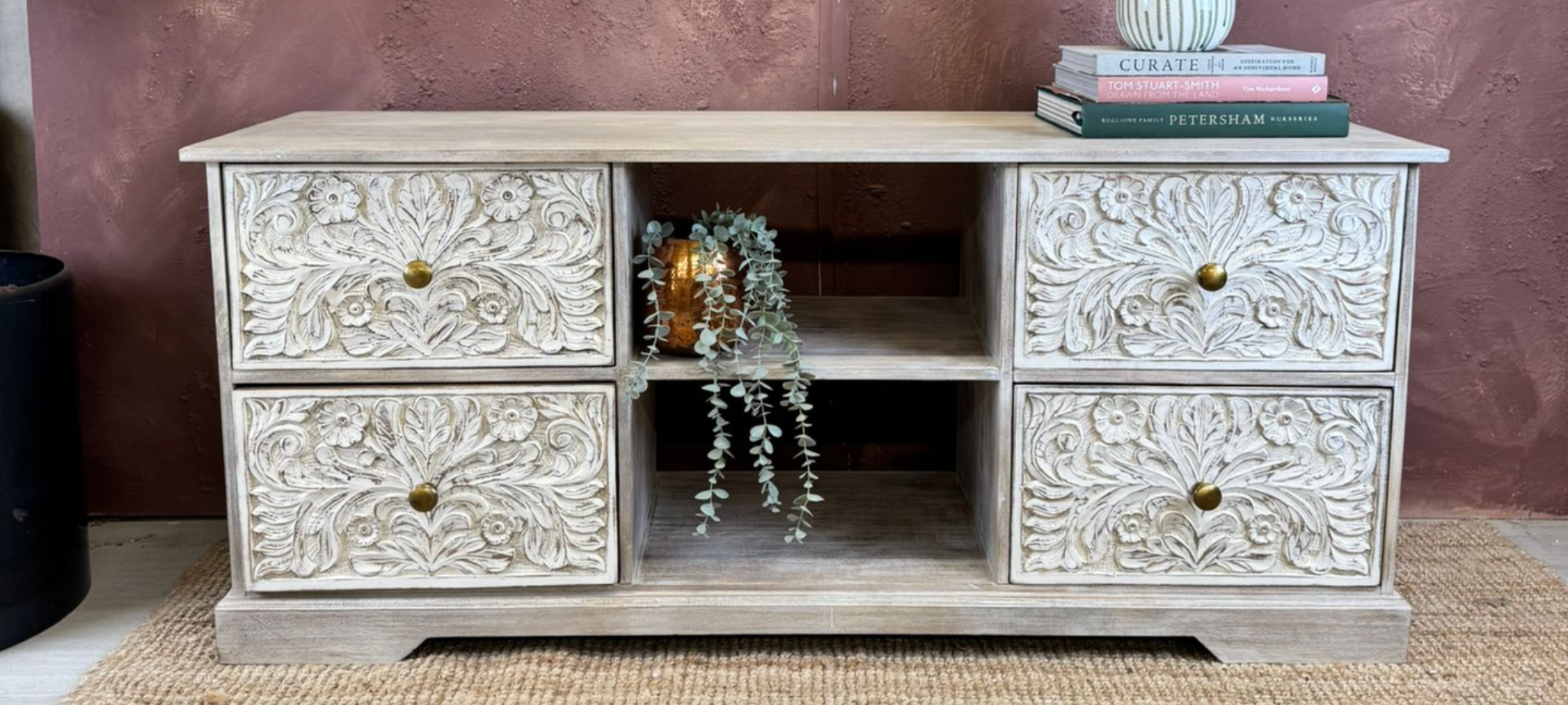 Decorative wooden TV cabinet with intricate carvings on a textured wall background