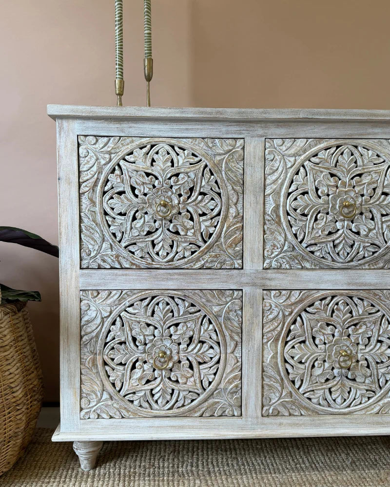 Close-up angled view of a whitewashed carved sideboard, styled with twisted candlesticks