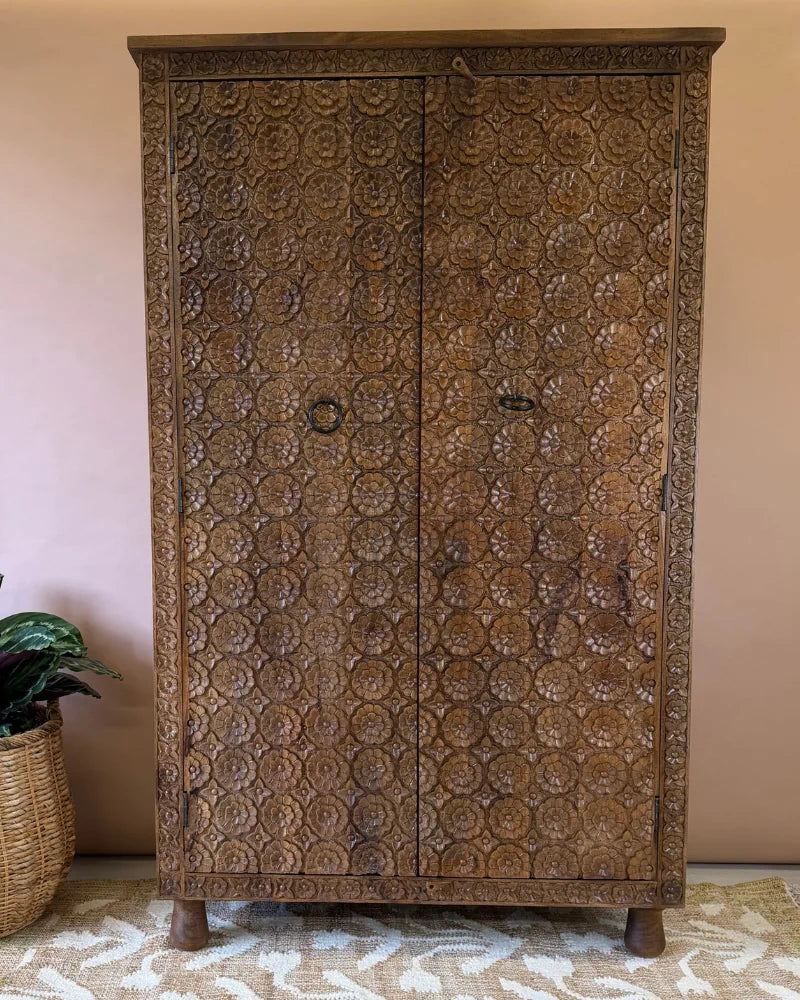 Tall carved mango wood wardrobe with all-over floral rosette carving and two doors, natural wood finish, front view