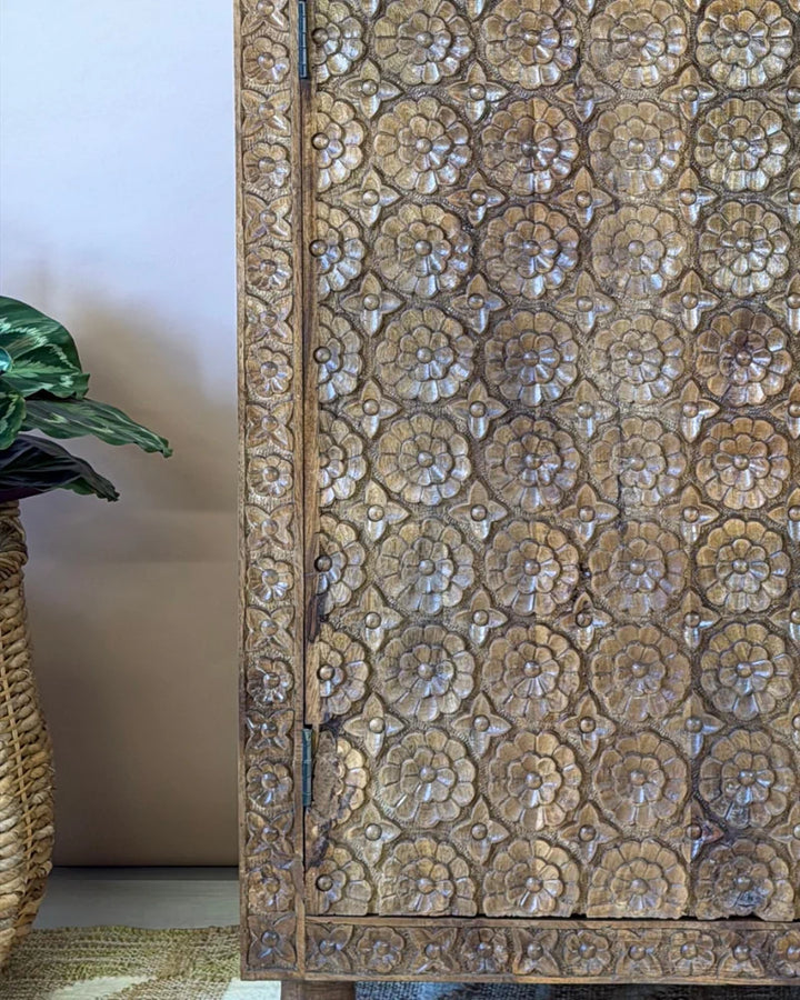 Close-up of the carved floral rosette detail on a mango wood wardrobe door panel