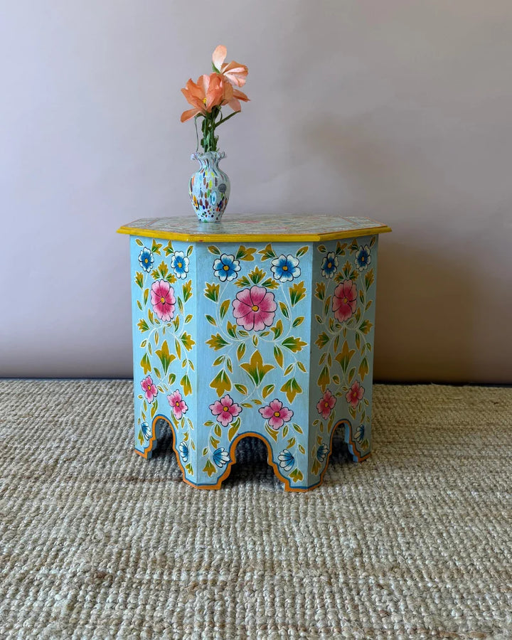 Hand-painted octagonal side table in pale blue with pink and blue floral design and scalloped skirt, front view