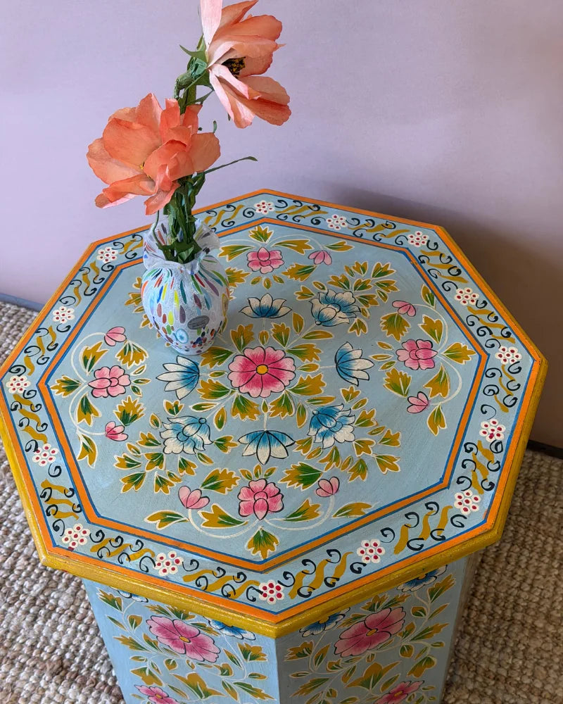 Close-up top-down view of a hand-painted octagonal side table's central floral medallion pattern