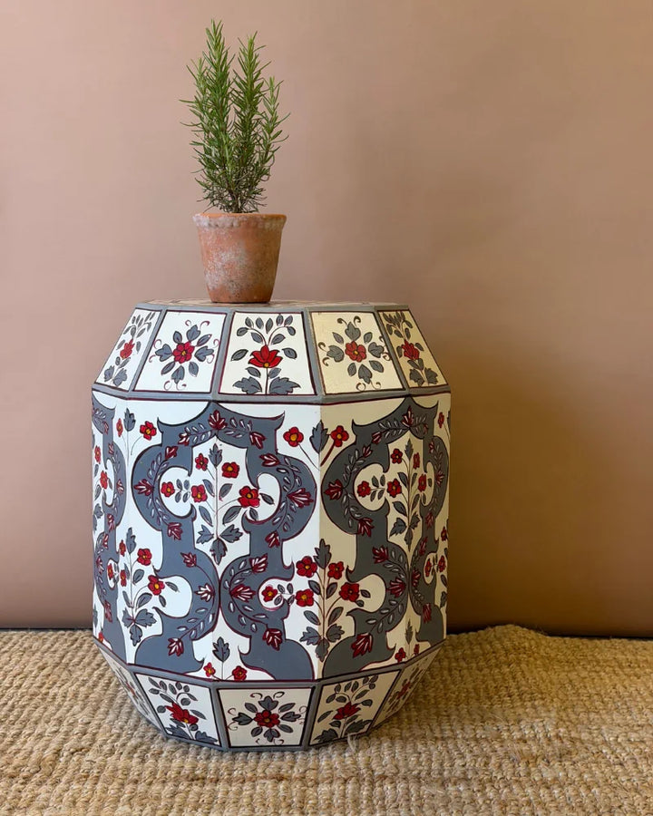 Hand-painted drum side table in grey and cream with red floral panels and a geometric arch motif, front view