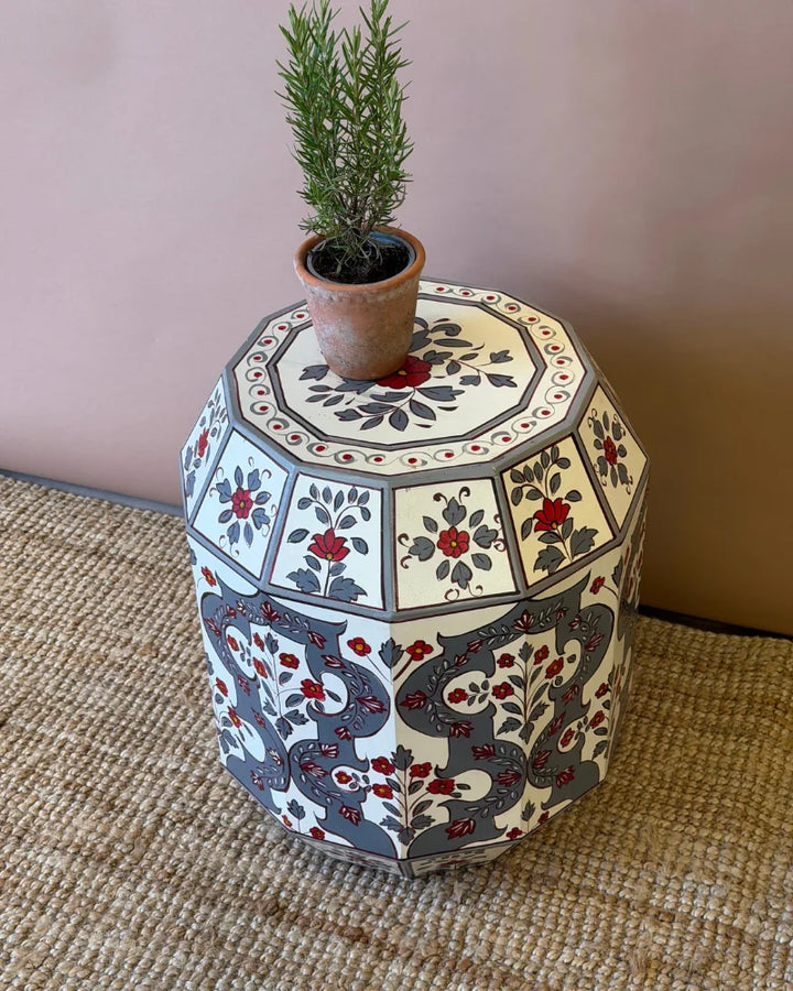 Hand-painted drum side table, angled top-down view showing grey, cream and red floral geometric design