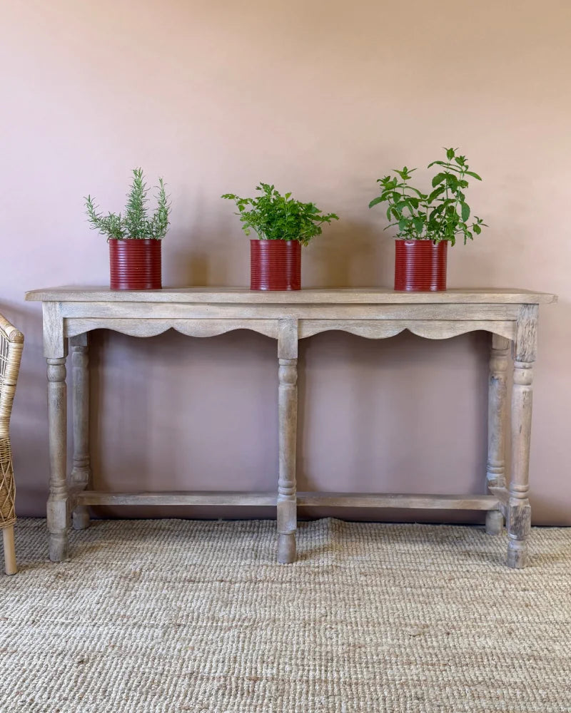 Weathered grey-wash console table with scalloped apron and turned legs, styled with herb plants in red tin planters