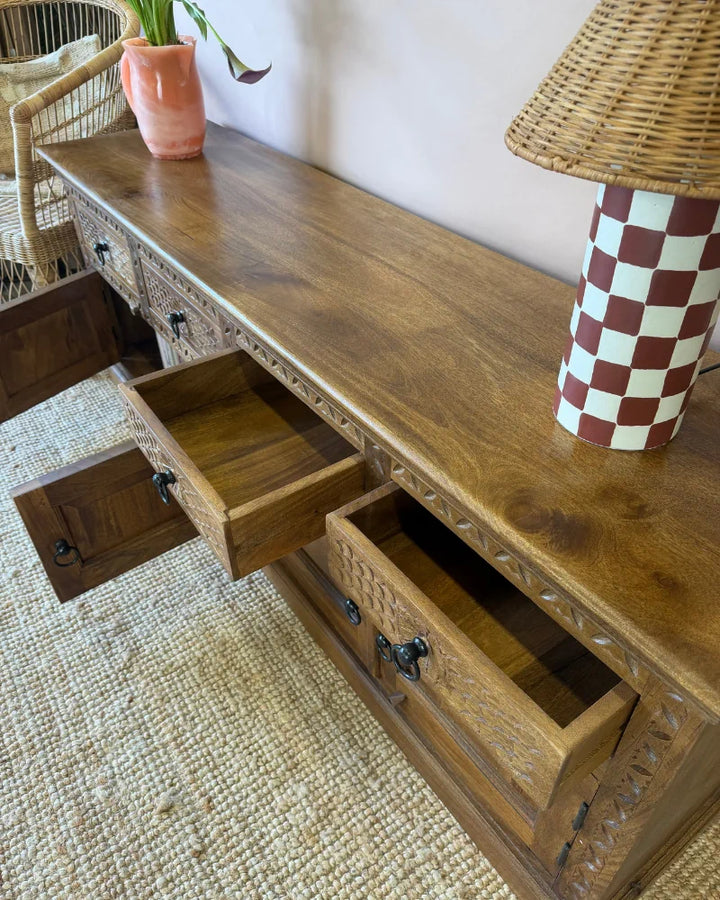 Close-up of open drawers on a carved wood sideboard, showing the natural wood interior