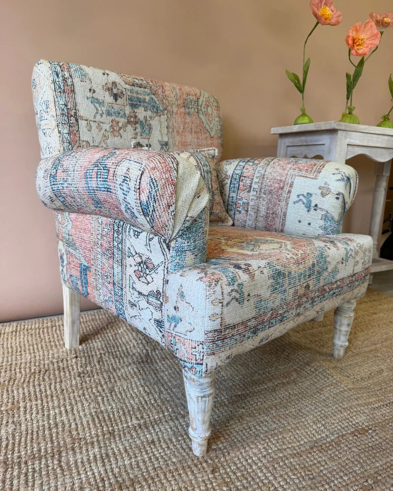 Armchair upholstered in vintage rug-print patchwork fabric with whitewashed turned legs, beside a whitewashed console table