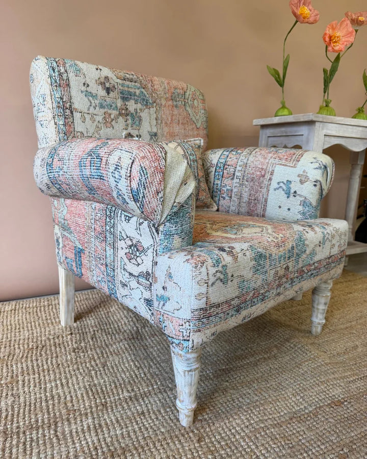Armchair upholstered in vintage rug-print patchwork fabric with whitewashed turned legs, beside a whitewashed console table