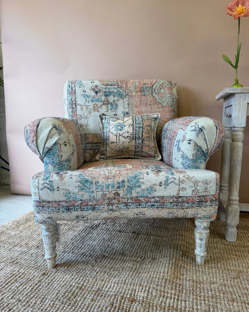Armchair in vintage rug-print patchwork fabric, angled view beside a whitewashed console table styled with poppies