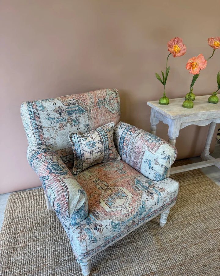 Close-up front view of an armchair upholstered in vintage rug-print patchwork fabric with a matching cushion