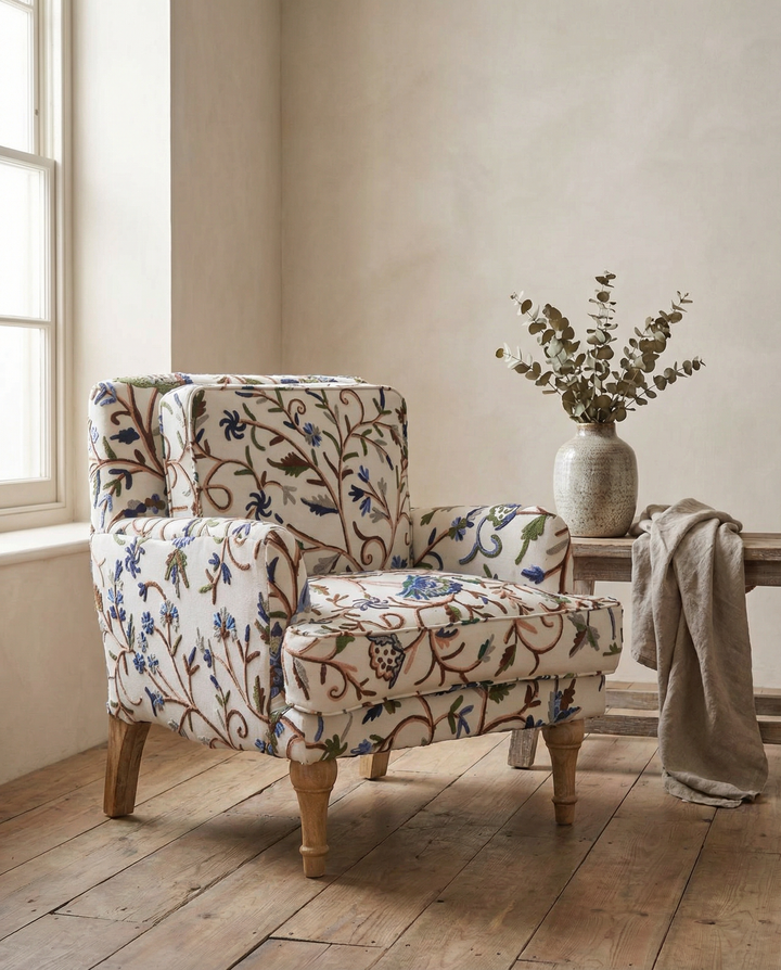 Patterned armchair and ottoman in a room with wooden floor and light-colored walls.