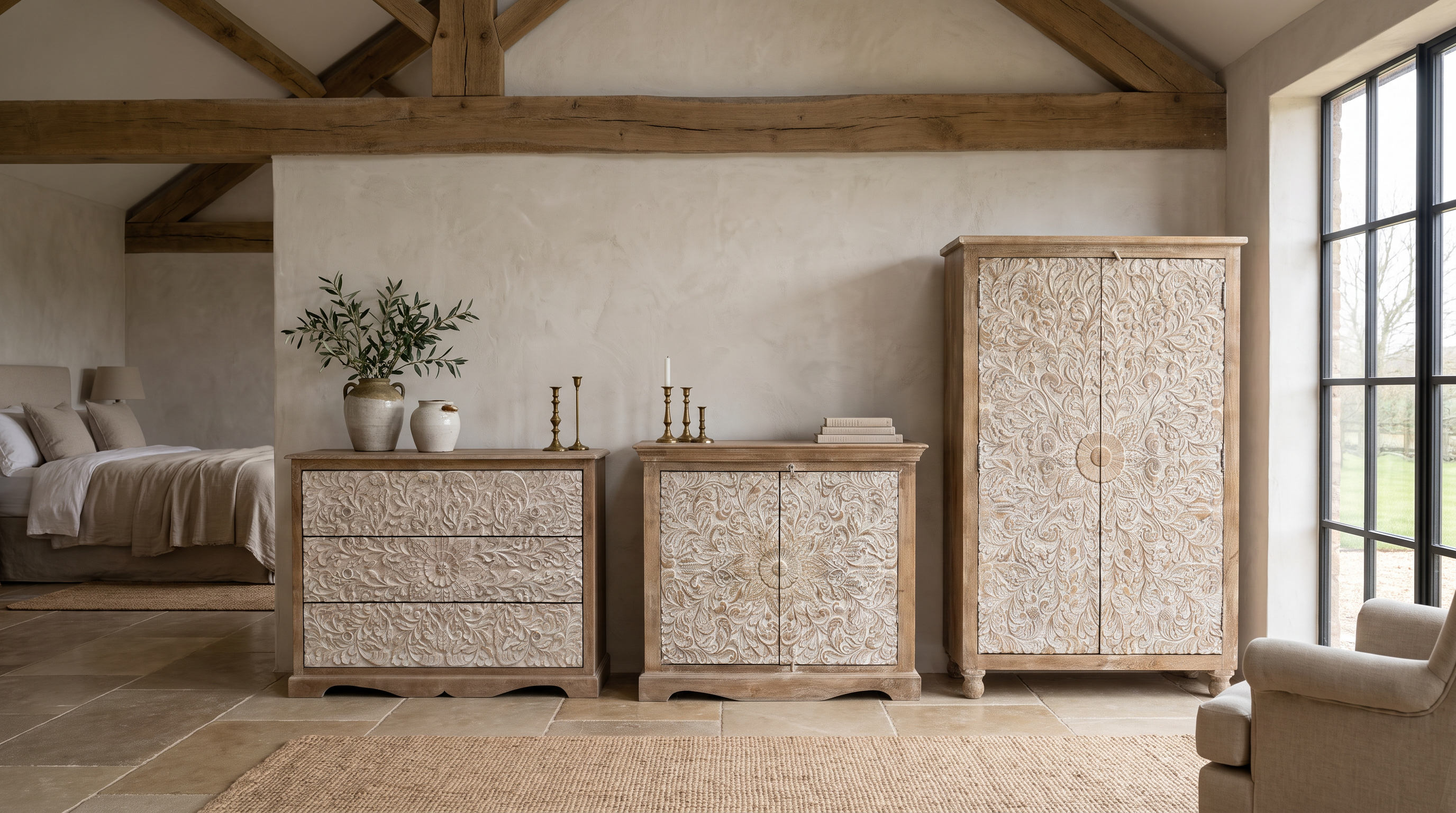 A rustic bedroom furniture set featuring a tall carved cabinet, a mid-century dresser, and a smaller cabinet, all in a light natural wood and textured beige finish, styled in a warm, rustic room with exposed wooden beams.